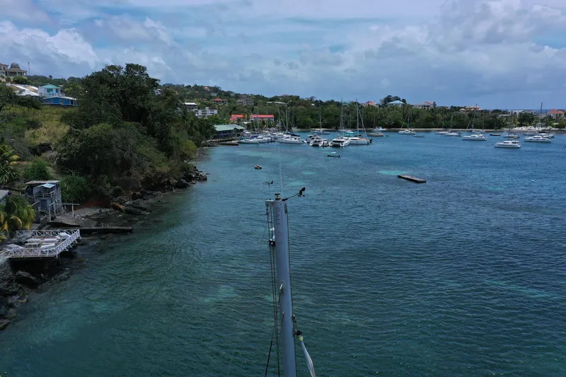 Slide: The Image of Coastal view with boats anchored in a serene bay, surrounded by lush greenery. - 8