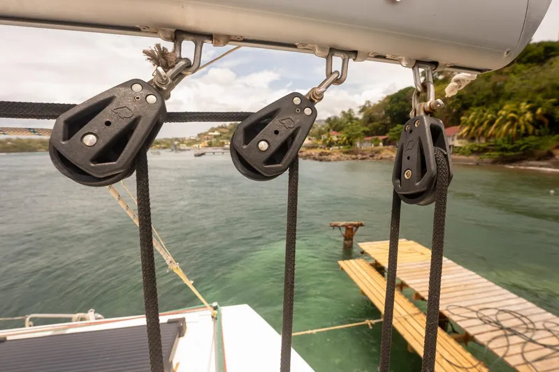 Slide: The Image of Sailing equipment on a Bali 4.1 catamaran, 2020, docked near a scenic shoreline. - 36