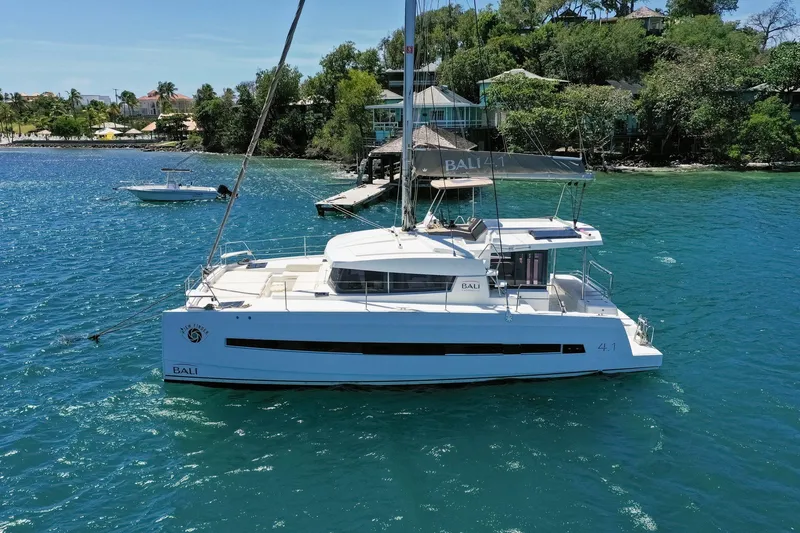 Slide: The Image of Sailing catamaran Bali 4.1, 2020 model, anchored near lush shoreline. - 43