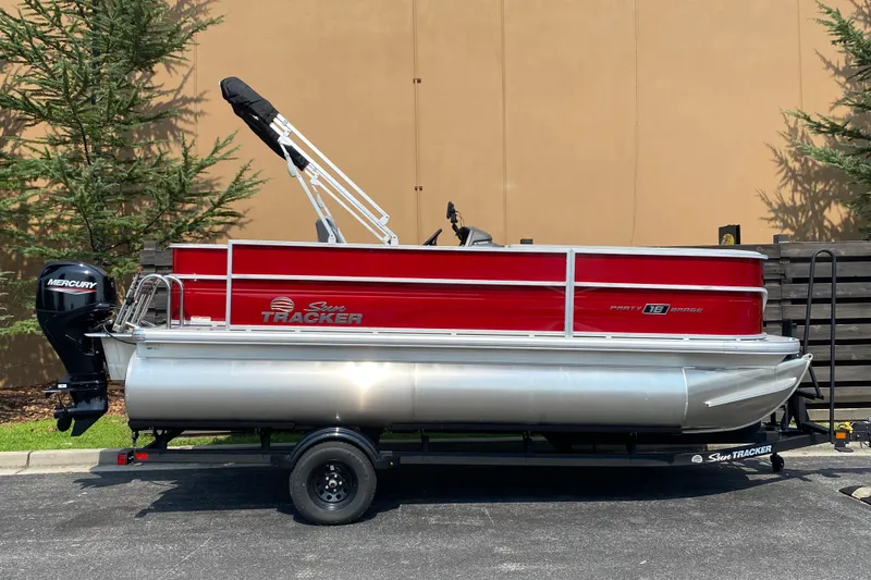 The Image of 2026 Sun Tracker Party Barge 18 DLX pontoon boat on trailer, red and silver design. - 0