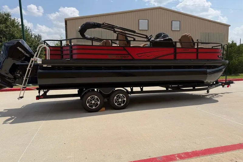 Slide: The Image of 2026 Ranger 223F pontoon boat on trailer, parked outdoors near a building. - 1