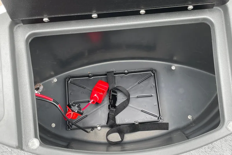 Slide: The Image of Battery compartment of 2026 Sun Tracker Bass Buggy 18 DLX with red cables and strap. - 15