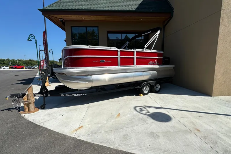 The Image of 2026 Sun Tracker Party Barge 20 DLX pontoon boat on trailer, parked outside building. - 0