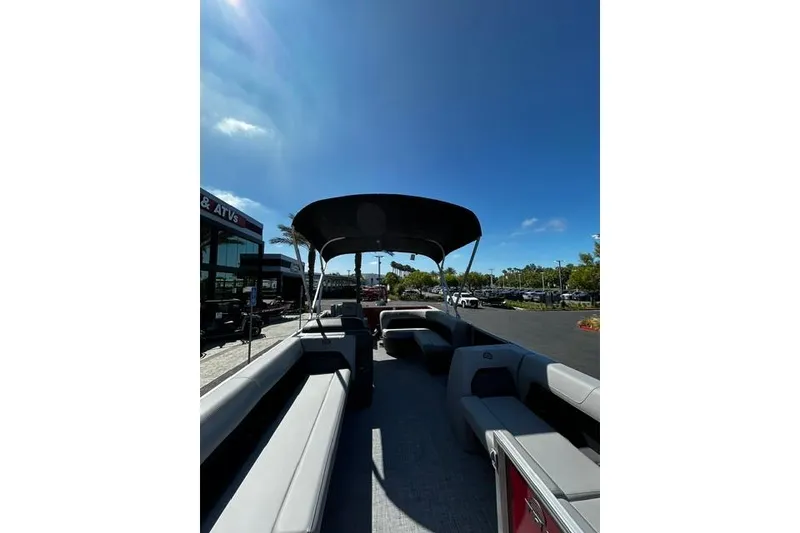 Slide: The Image of 2026 Sun Tracker Party Barge 18 DLX pontoon boat with canopy under clear blue sky. - 3
