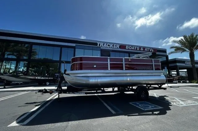 Slide: The Image of 2026 Sun Tracker Party Barge 18 DLX pontoon boat parked outside Tracker Boats dealership. - 11