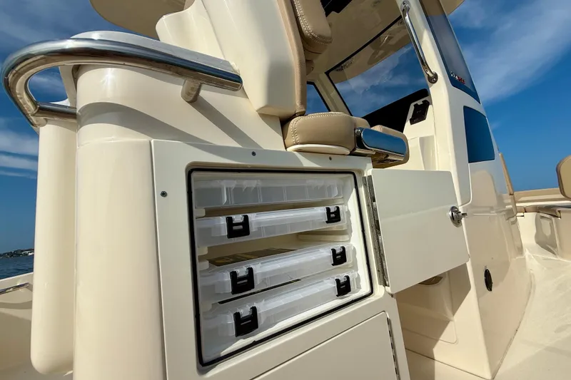 Slide: The Image of 2026 Scout 261 XSS boat with open storage compartments under a clear blue sky. - 31