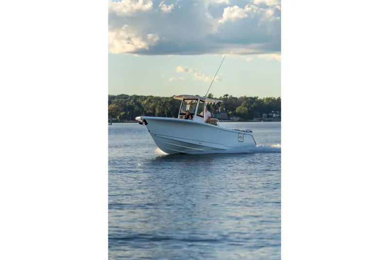 Slide: The Image of 2026 Sea Hunt Ultra 275 Coffin Box boat cruising on a serene lake under a cloudy sky. - 54