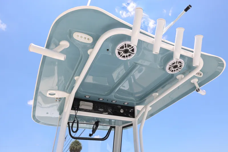 Slide: The Image of 2027 Sea Hunt Gamefish 25 T-top with rod holders and speakers against blue sky. - 20
