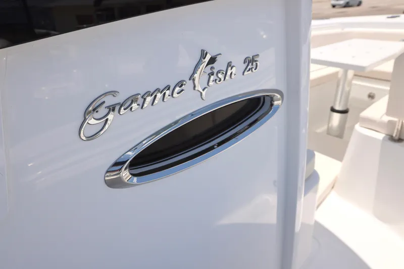 Slide: The Image of 2027 Sea Hunt Gamefish 25 boat emblem on sleek white surface. - 9