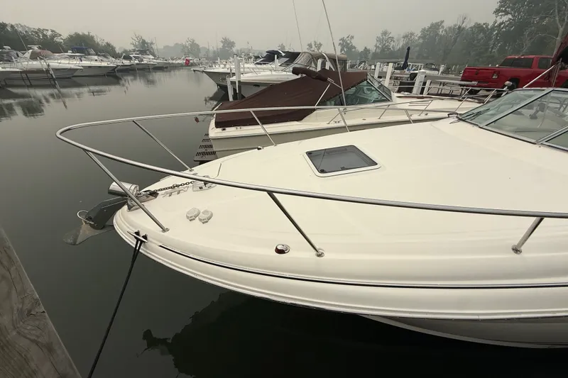 Slide: The Image of 2004 Sea Ray Sundancer 280 docked in a marina, surrounded by calm waters and other boats. - 2