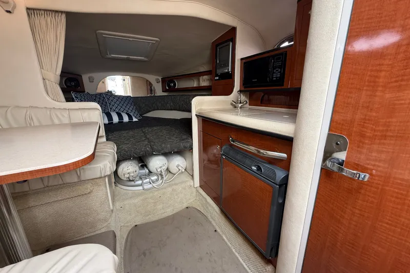 Slide: The Image of Interior of 2004 Sea Ray Sundancer 280, featuring kitchenette and cozy sleeping area. - 12