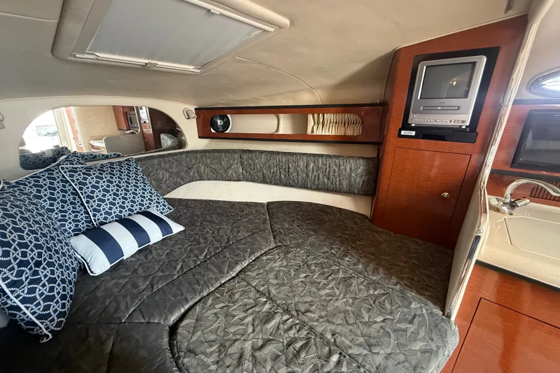 Slide: The Image of Interior of 2004 Sea Ray Sundancer 280 with cozy bed, pillows, and TV. - 14