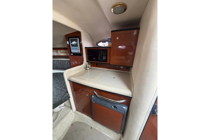 Slide: The Image of 2004 Sea Ray Sundancer 280 interior kitchenette with sink, microwave, and storage cabinets. - 13