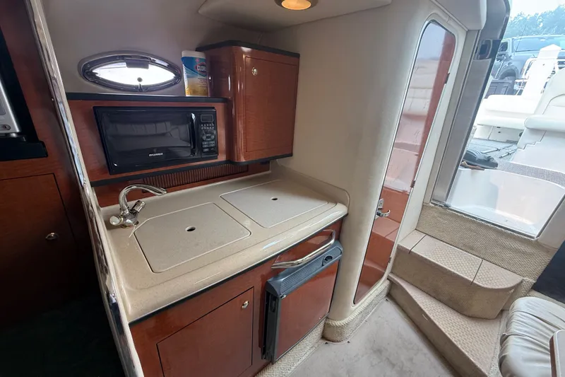 Slide: The Image of 2004 Sea Ray Sundancer 280 interior kitchen with microwave, sink, and cabinetry. - 19