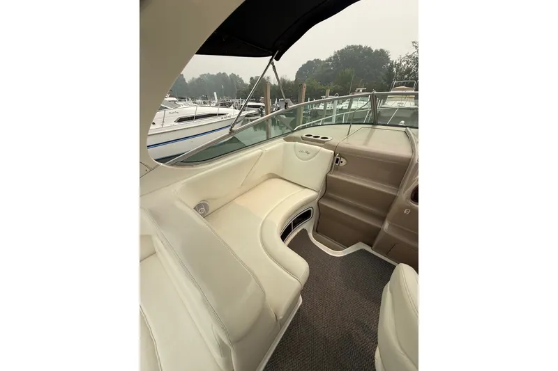 Slide: The Image of 2004 Sea Ray Sundancer 280 interior with white seating and helm, docked at marina. - 8
