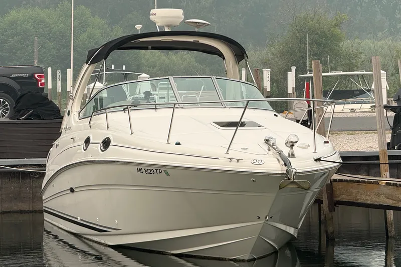 The Image of 2004 Sea Ray Sundancer 280 in a calm marina, featuring sleek lines and a black canopy. - 0