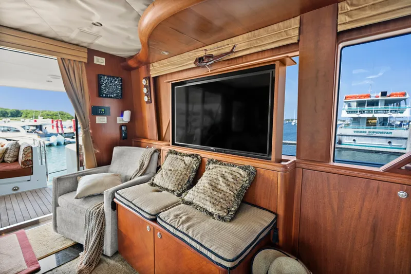 Slide: The Image of Luxurious 2004 Cheoy Lee Flybridge yacht interior with cozy seating and large TV, overlooking marina. - 22