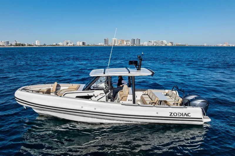 Slide: The Image of 2025 Zodiac X10CC boat cruising on blue ocean with city skyline in background. - 9