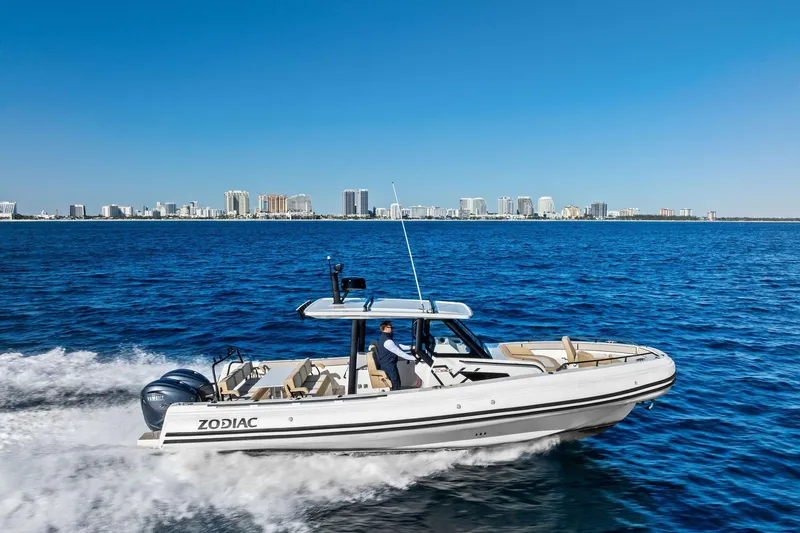 Slide: The Image of 2025 Zodiac X10CC boat cruising on blue ocean with city skyline in background. - 0