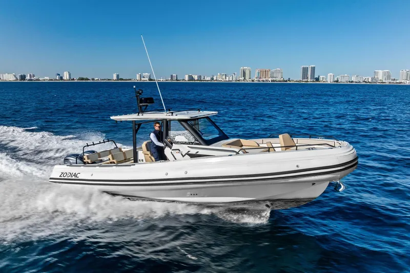 Slide: The Image of 2025 Zodiac X10CC boat cruising on blue ocean with city skyline in background. - 7