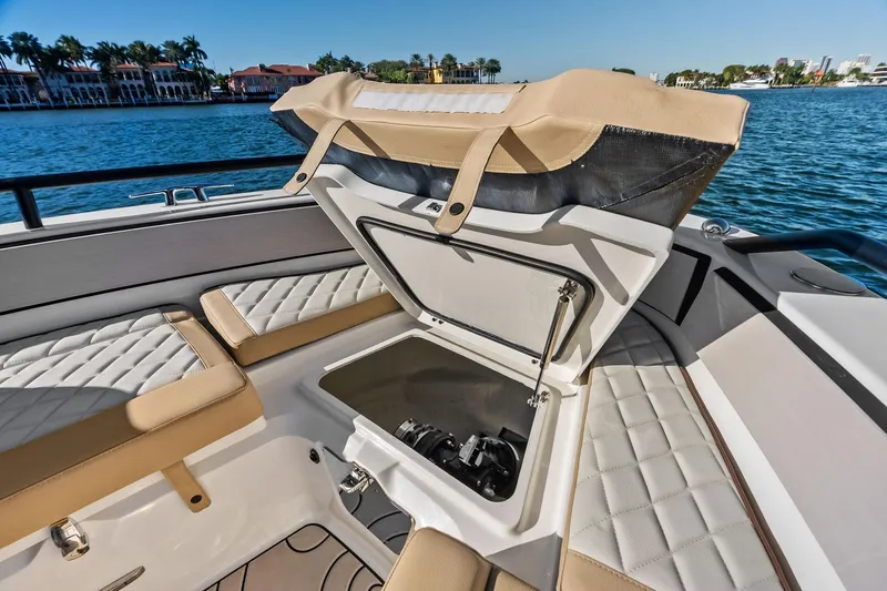 Slide: The Image of 2025 Zodiac X10CC boat interior with open storage compartment, quilted seating, and scenic waterfront view. - 46