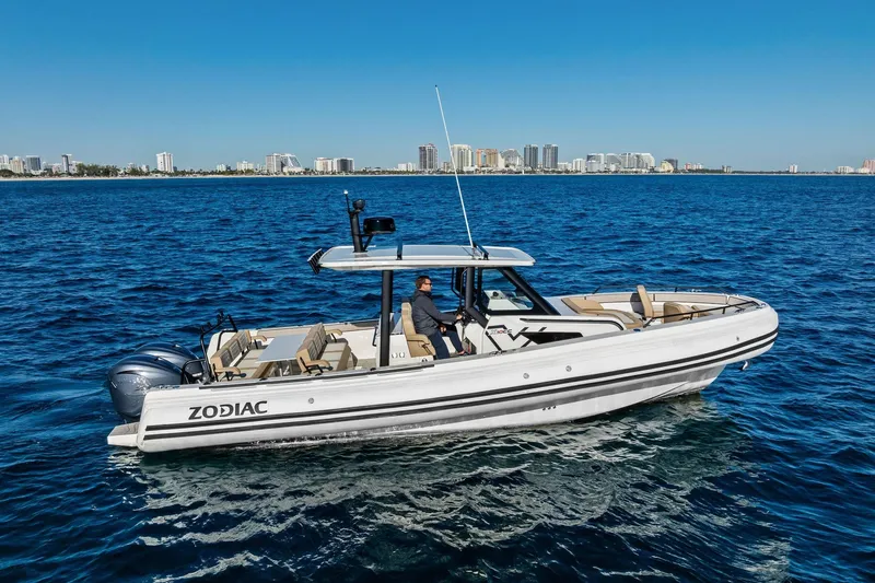 Slide: The Image of 2025 Zodiac X10CC boat cruising on blue ocean with city skyline in background. - 13