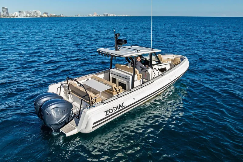 Slide: The Image of 2025 Zodiac X10CC boat cruising on open blue water with city skyline in background. - 14