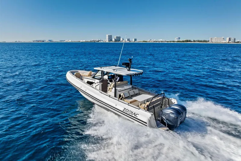 Slide: The Image of 2025 Zodiac X10CC boat cruising on open blue water with city skyline in background. - 3