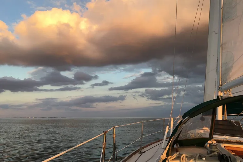 Slide: The Image of Sailing on a 1983 Sabre 38 yacht under dramatic sunset clouds over calm waters. - 15