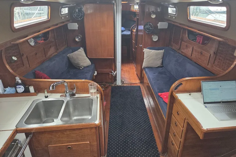 Slide: The Image of Interior of a 1983 Sabre 38 sailboat with wooden cabinetry and blue seating. - 17
