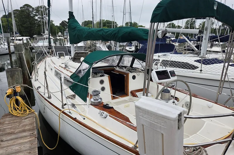 Slide: The Image of 1983 Sabre 38 sailboat docked at marina, featuring green canvas covers and wooden accents. - 2