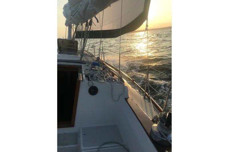 Slide: The Image of 1983 Sabre 38 sailboat cruising at sunset on open water. - 12