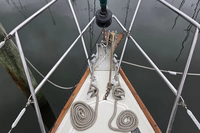 Slide: The Image of Bow of 1983 Sabre 38 sailboat with coiled ropes and anchor, docked on calm water. - 4