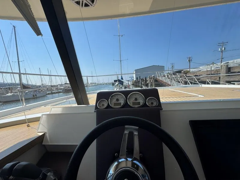 Slide: The Image of The image shows the helm of a 2016 Fountaine Pajot Motor Yacht 37 in a marina. - 20