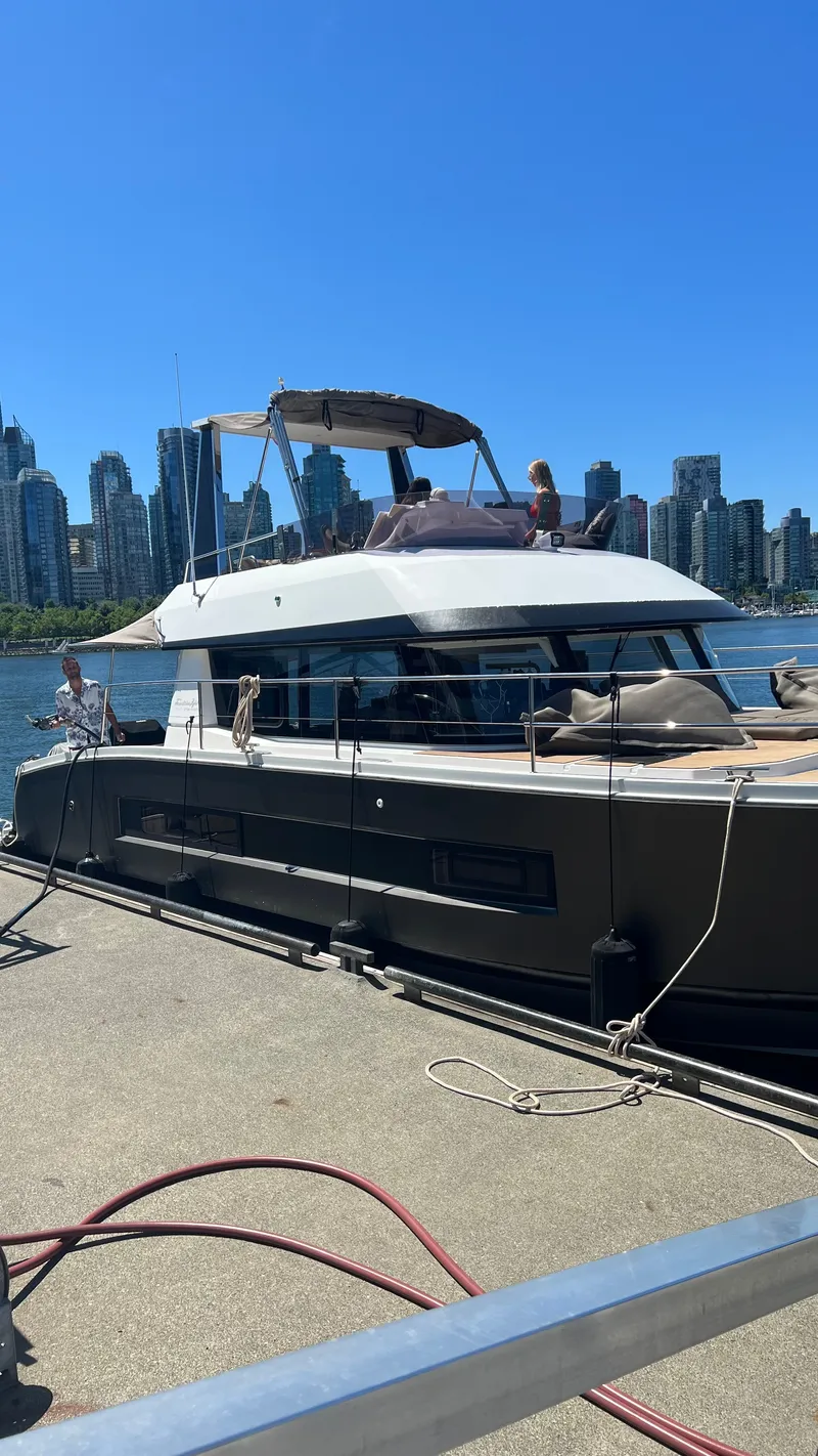Slide: The Image of A 2016 Fountaine Pajot Motor Yacht 37 docked with a city skyline in the background. - 2