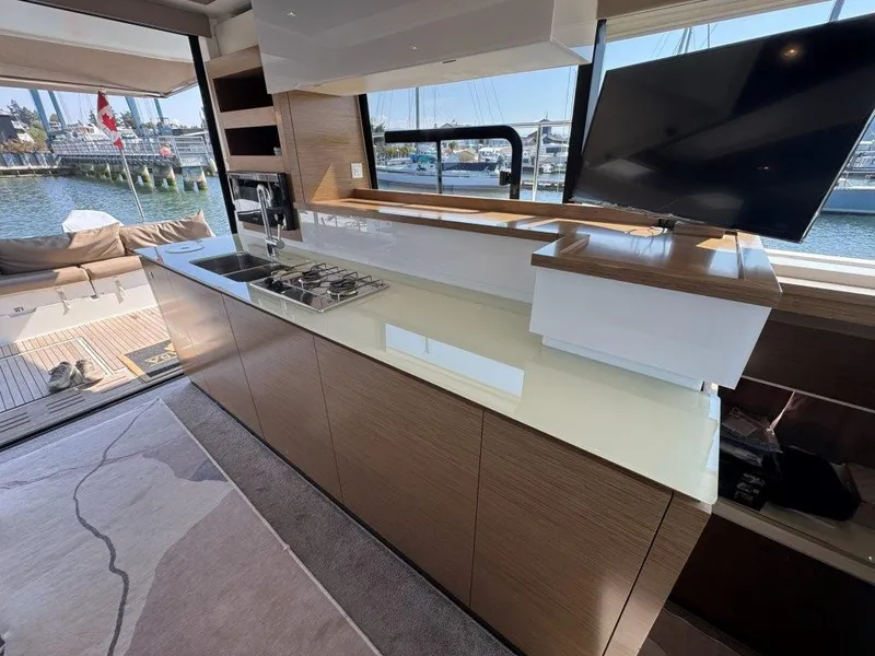 Slide: The Image of Interior view of a modern yacht kitchen with wooden cabinets, stove, sink, and TV. Harbor in the background. - 10