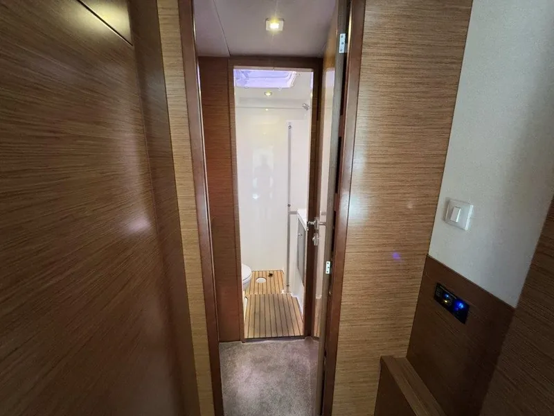 Slide: The Image of A narrow hallway leads to a bathroom with wooden flooring and skylights. - 26