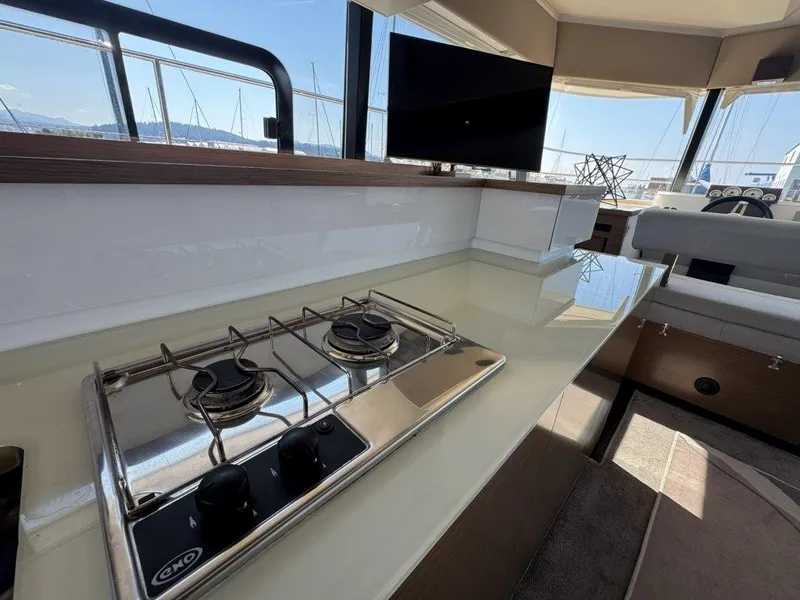 Slide: The Image of The interior of a 2016 Fountaine Pajot Motor Yacht 37 features a modern kitchen with a two-burner stove and a flat-screen TV. - 11