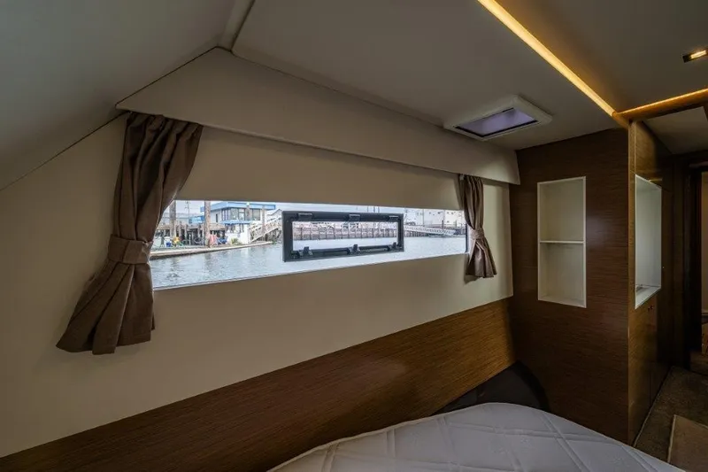 Slide: The Image of Interior of a yacht with a window overlooking a harbor. Wooden walls and curtains are visible. - 32