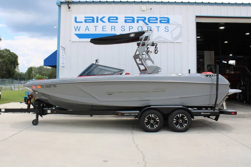 The Image of A gray 2021 Super Air Nautique GS22 boat on a trailer in front of a building. - 1