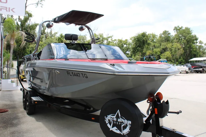 Slide: The Image of A gray 2021 Nautique Super Air Nautique GS22 boat on a trailer, surrounded by trees. - 4