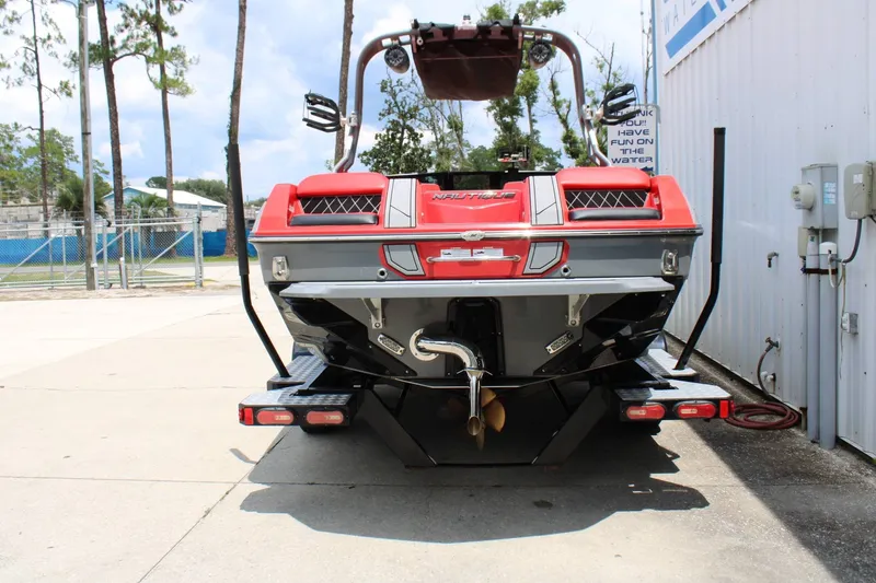 Slide: The Image of A red 2021 Nautique Super Air Nautique GS22 boat on a trailer beside a building. - 27