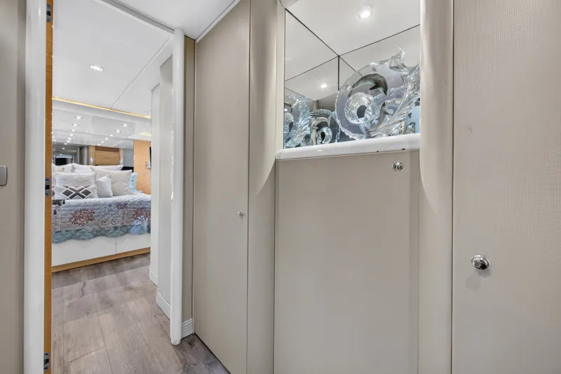 Slide: The Image of A sleek hallway with wood flooring leads to a bedroom, featuring a decorative mirror and sculptures. - 23
