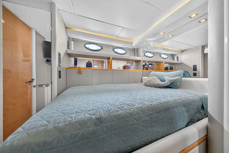 Slide: The Image of The 2001 Lazzara 80 SL cabin features a cozy bed with a blue quilt and portholes. - 39