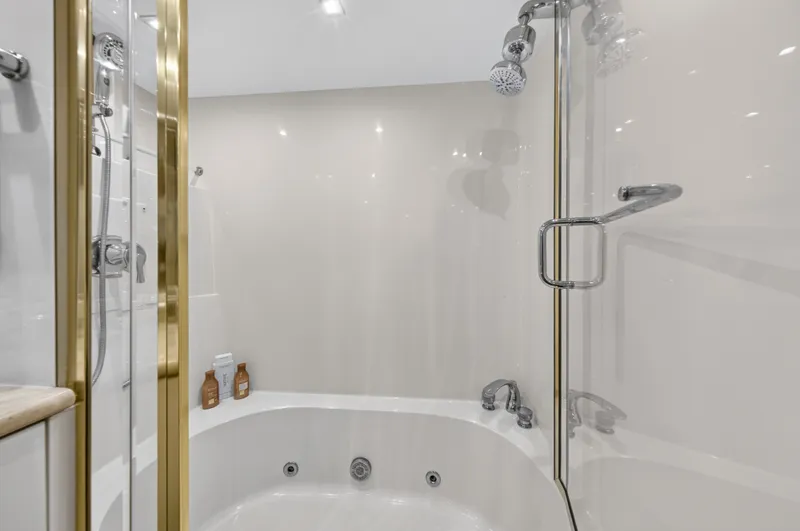 Slide: The Image of Luxurious bathroom with a whirlpool tub and gold fixtures on a Lazzara 80 SL yacht. - 29