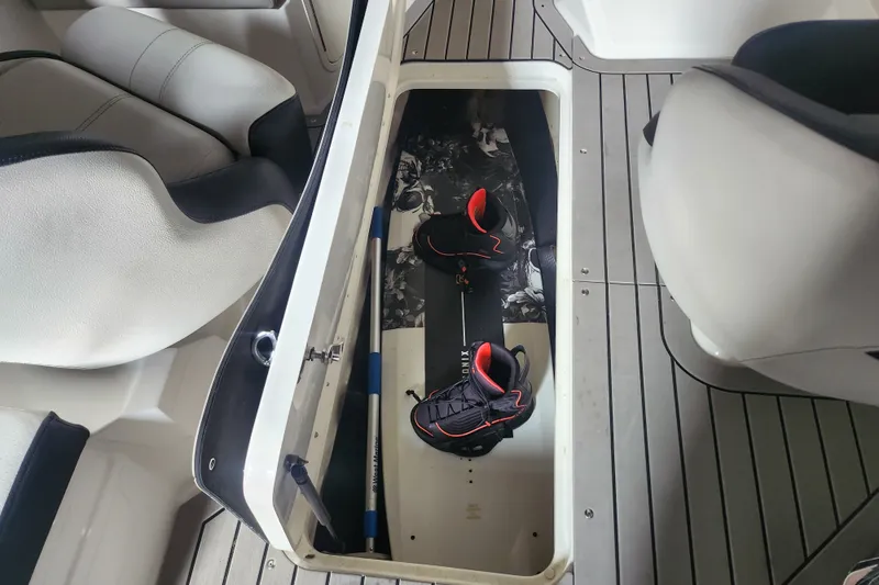 Slide: The Image of Storage compartment in 2022 Sea Ray SPX 210 Outboard with wakeboard and shoes. - 15