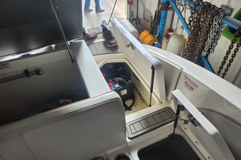 Slide: The Image of 2022 Sea Ray SPX 210 Outboard interior with open storage compartments in a workshop setting. - 12