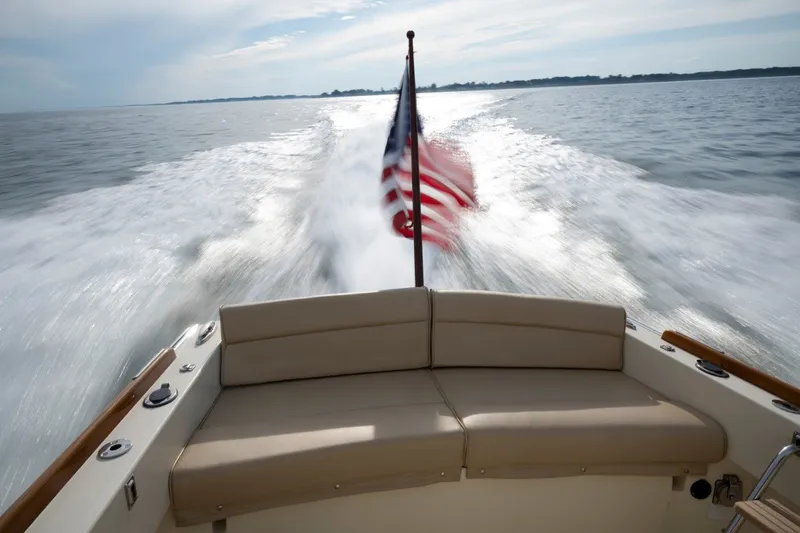 Slide: The Image of 2014 Hinckley Talaria 29C cruising on water, American flag waving, rear view. - 8