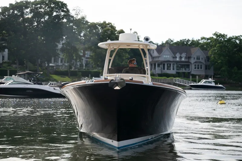 Slide: The Image of 2014 Hinckley Talaria 29C boat cruising on a serene lake near luxury homes. - 30