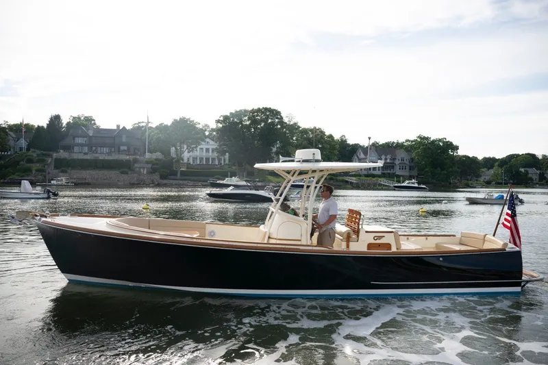 Slide: The Image of 2014 Hinckley Talaria 29C cruising on a scenic waterfront with houses in the background. - 6
